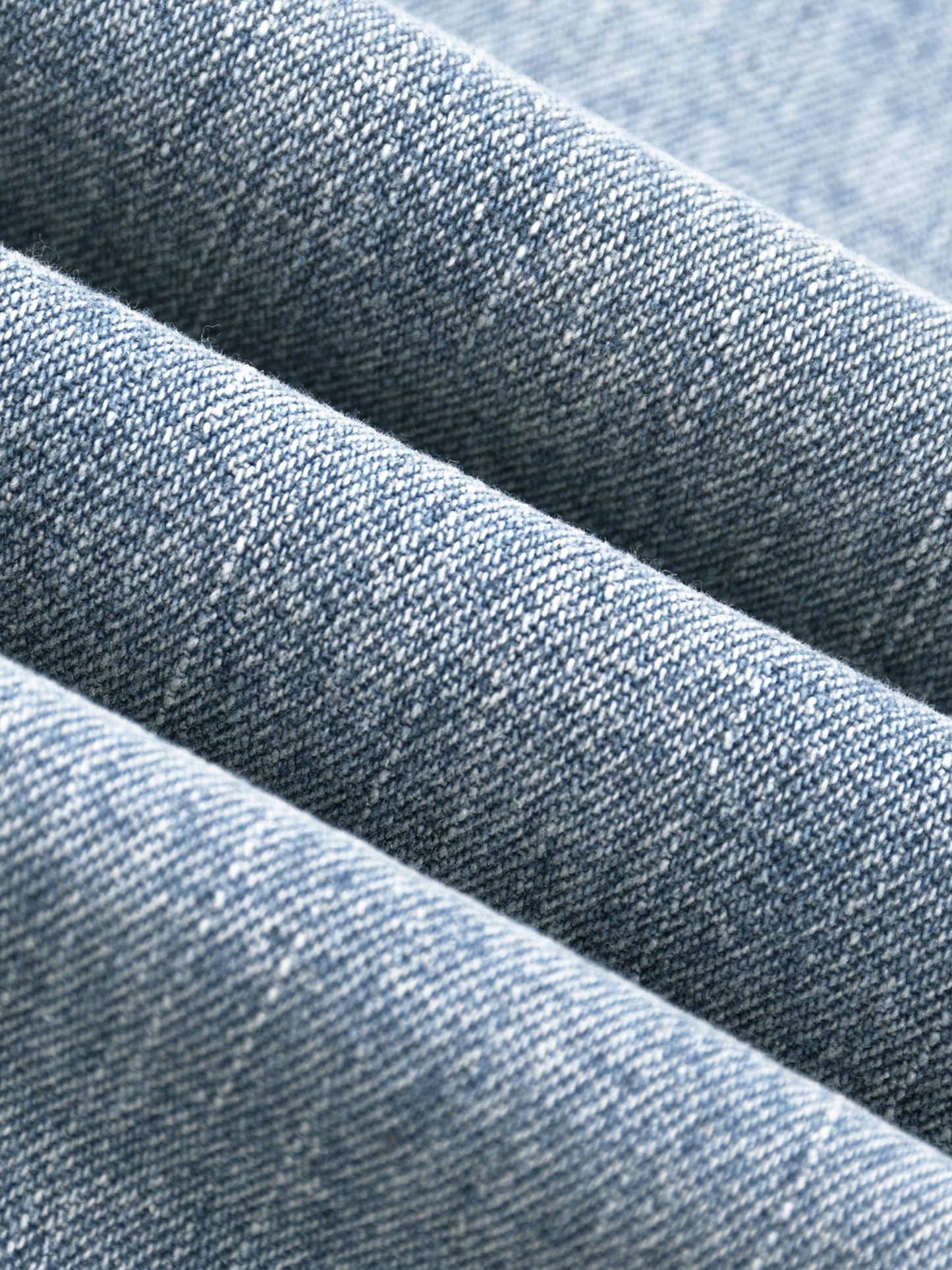 Macro close-up view of the premium heavyweight vintage wash denim fabric, highlighting the textured weave and dual-tone yarn fibers.