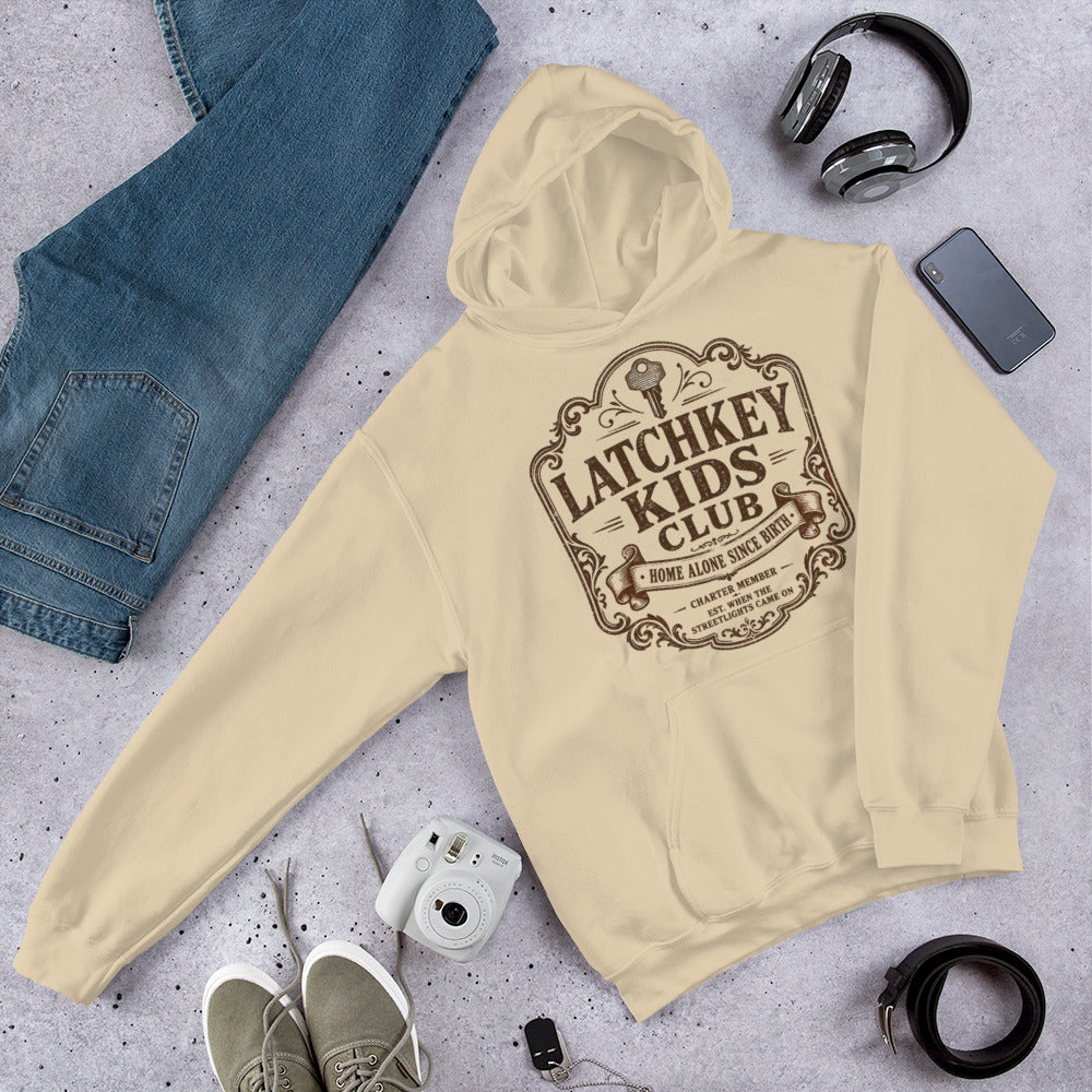 Flat lay arrangement of Latchkey Kids Club graphic hoodie with headphones and sunglasses
