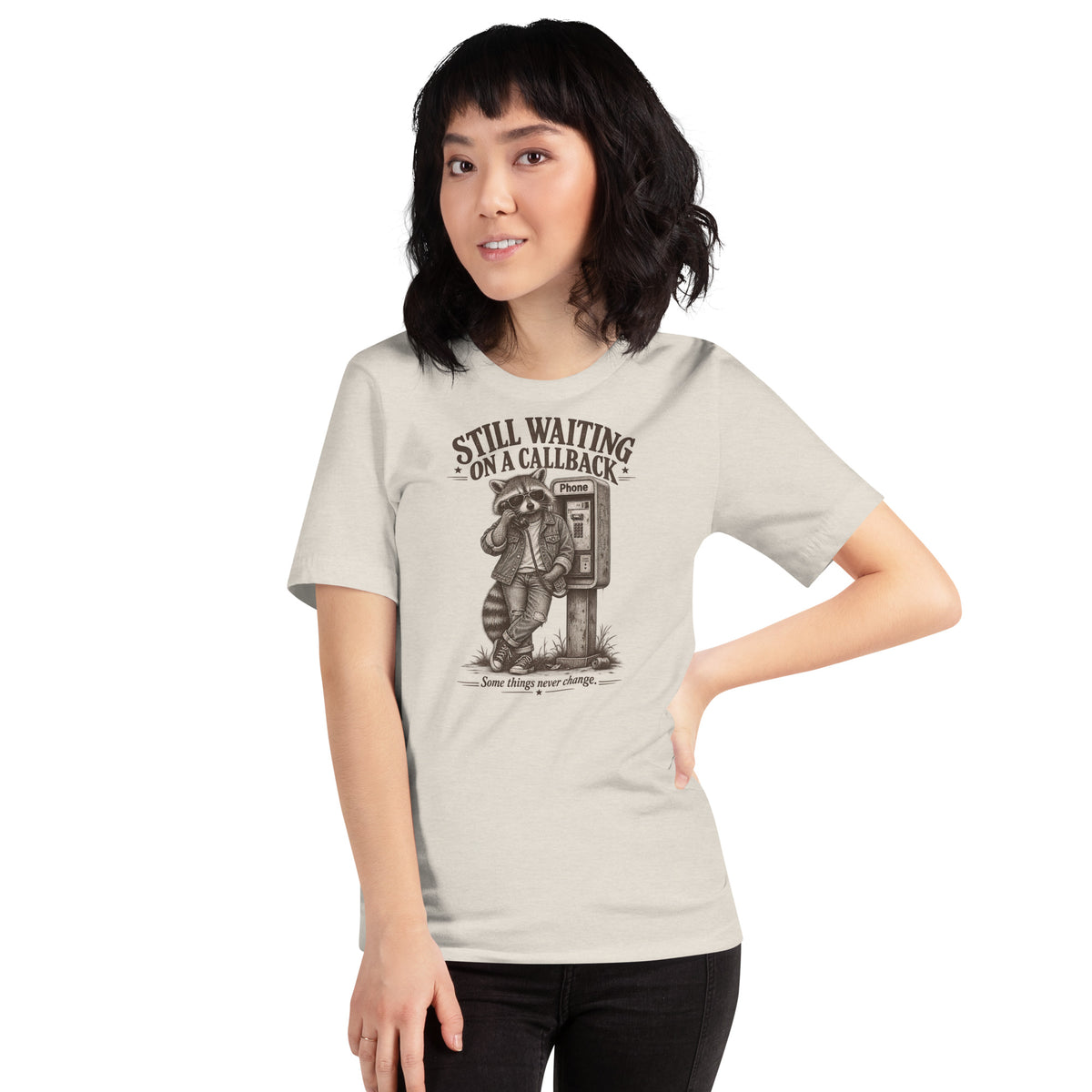 Female model wearing Still Waiting on a Callback funny raccoon graphic t-shirt in heather dust
