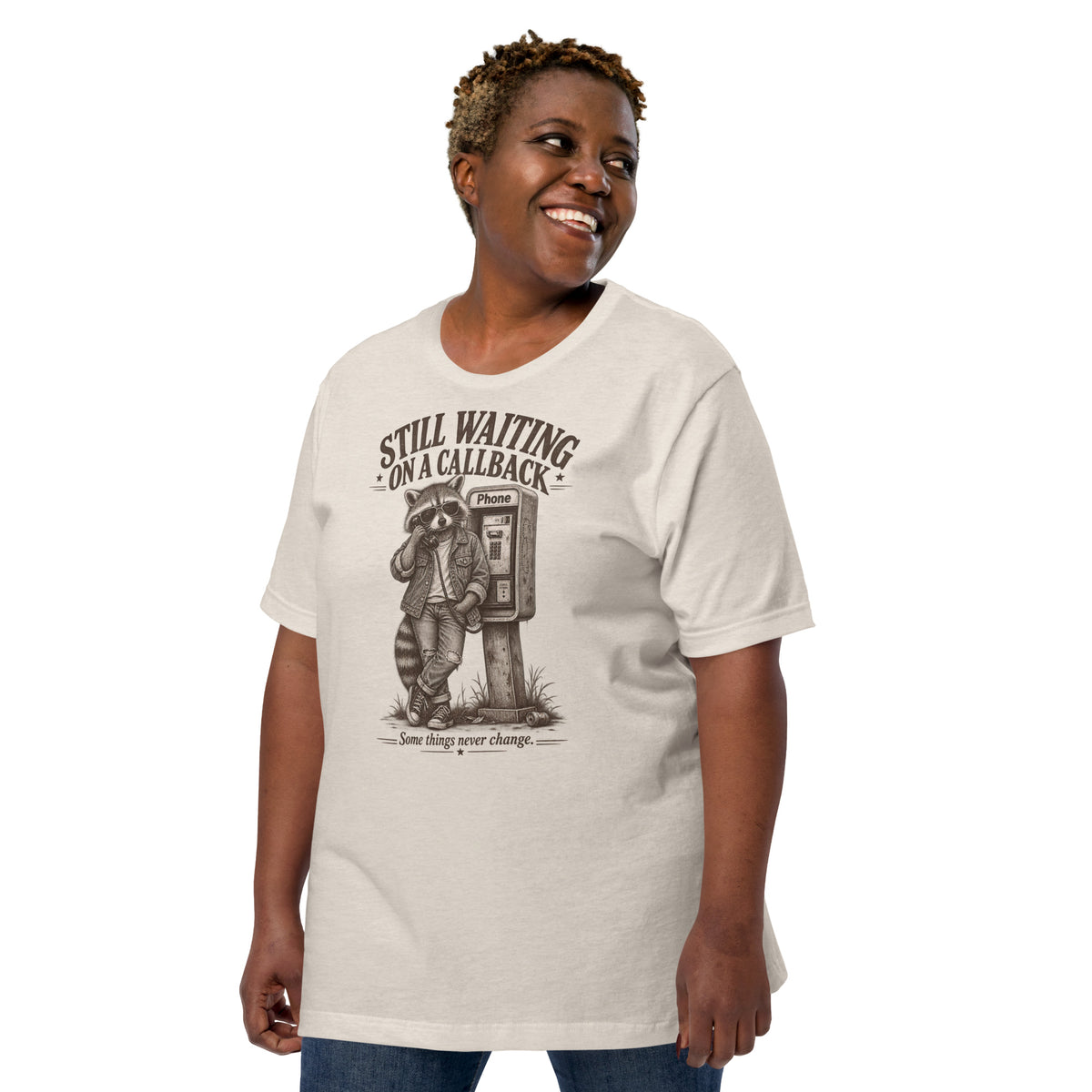Smiling person modeling Still Waiting on a Callback funny raccoon graphic t-shirt in heather dust