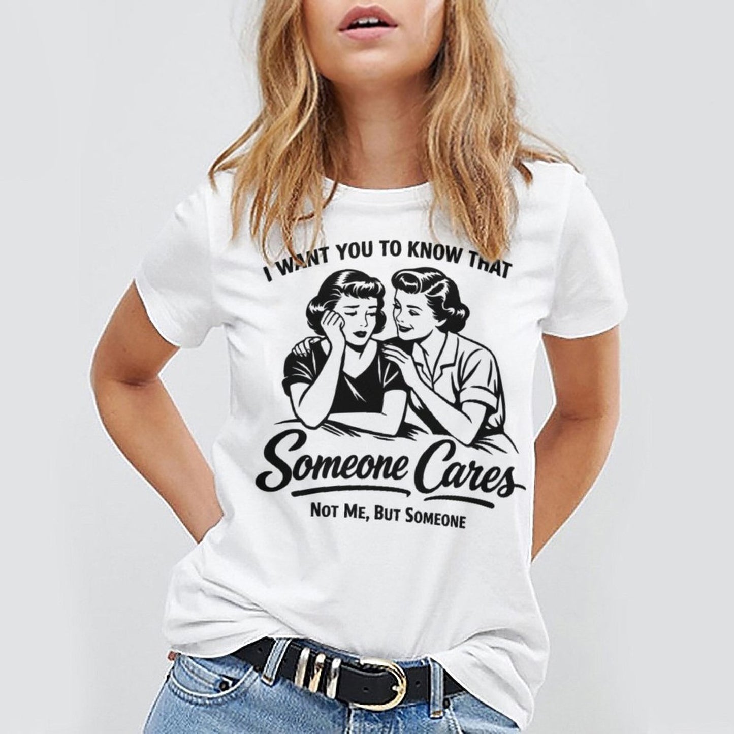 A woman wearing a white short sleeve graphic crewneck t-shirt featuring a black vintage pop-art illustration and the sarcastic quote I WANT YOU TO KNOW THAT Someone Cares NOT ME, BUT SOMEONE.