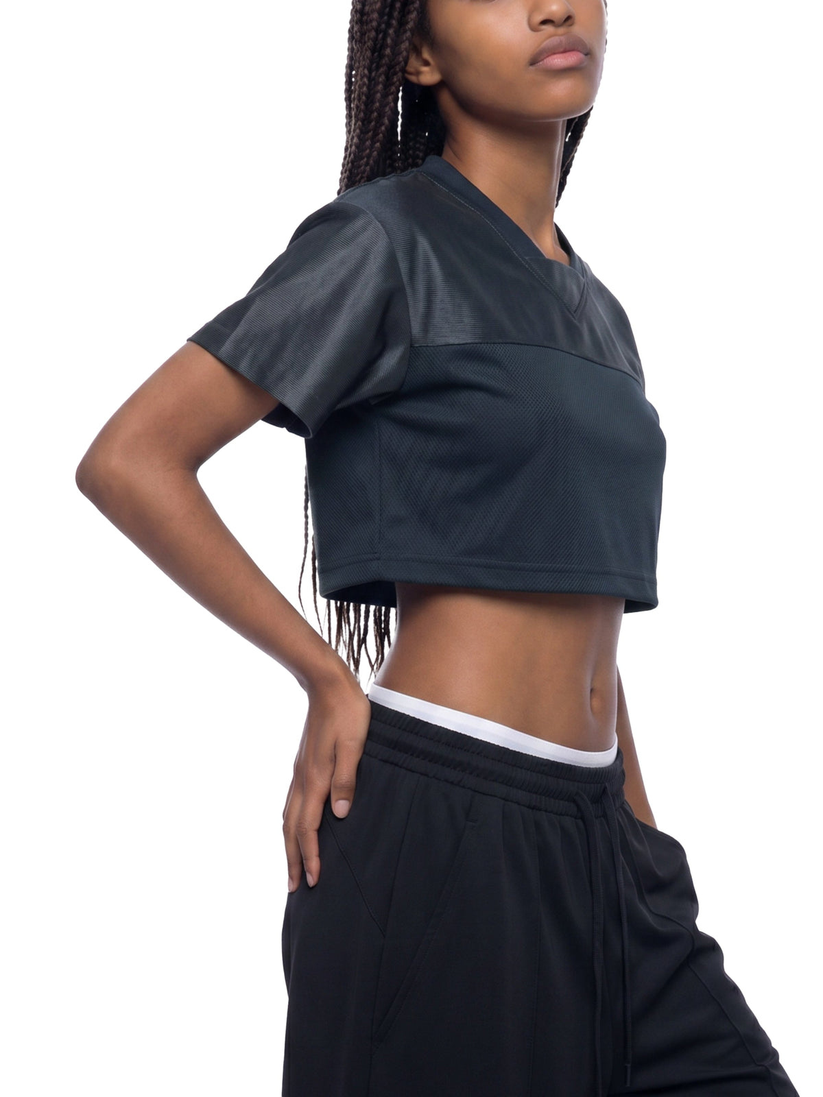 Clothing By Hot Takes Designs black cropped V-neck jersey with paneled detailing worn by a model in a studio.