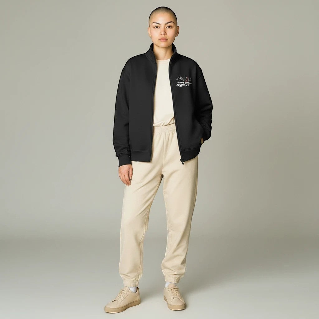 Clothing By Hot Takes Designs black Stray Kids Run It full zip track jacket worn by a model with beige joggers