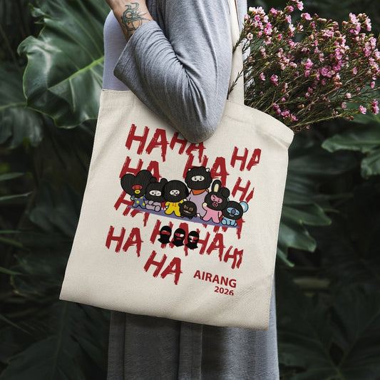 Aesthetic outdoor view of the BT21 Hooligan canvas tote bag resting against green leaves in natural sunlight.