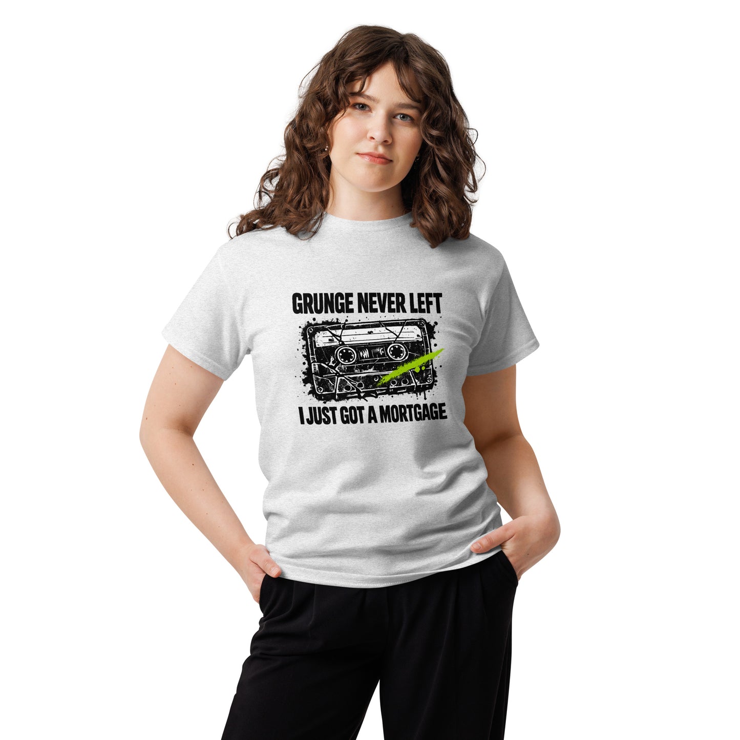 Female model wearing an ash gray unisex t-shirt featuring a distressed 90s cassette tape graphic with the text "Grunge Never Left I Just Got a Mortgage"