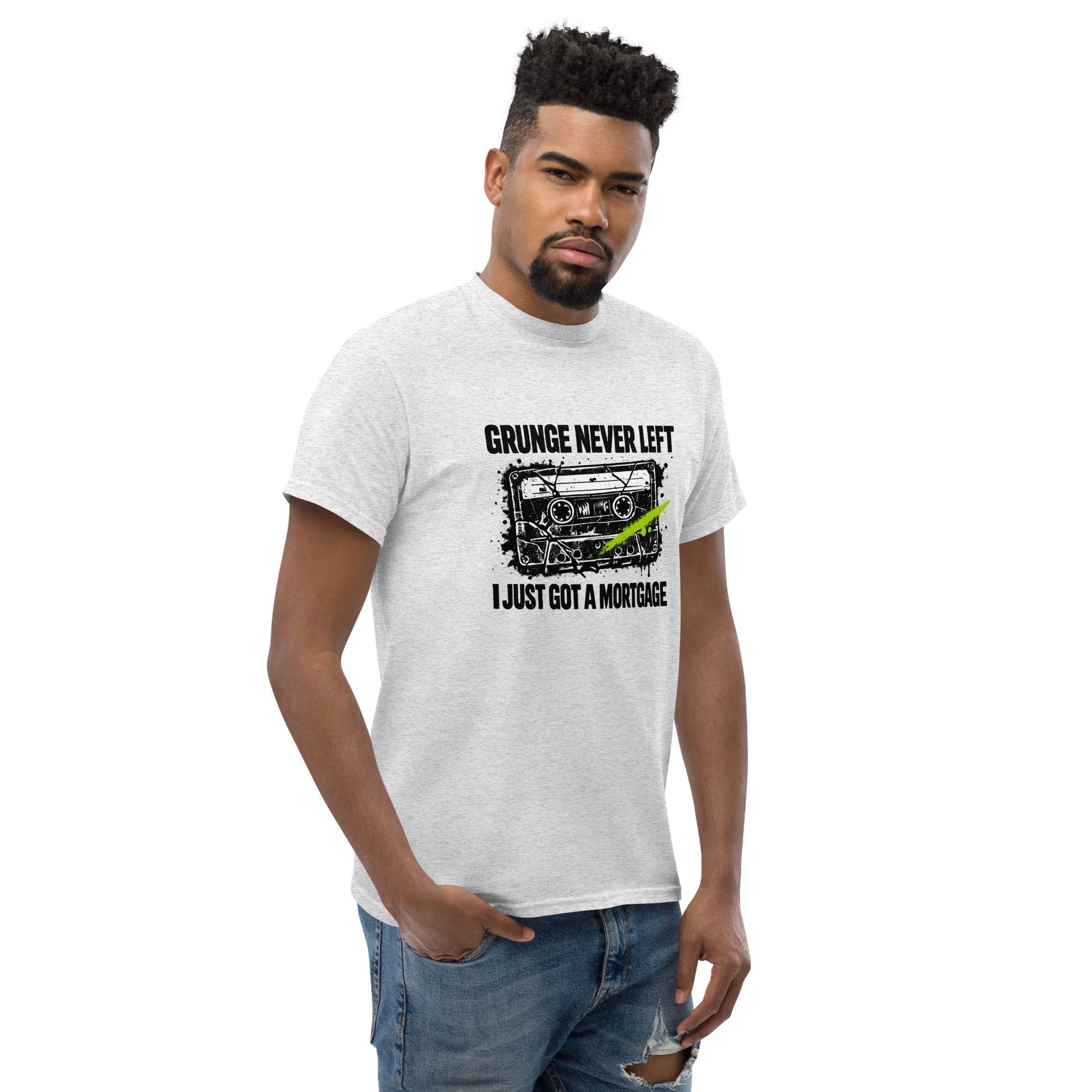 Male model wearing an ash gray unisex t-shirt featuring a distressed 90s cassette tape graphic with the text "Grunge Never Left I Just Got a Mortgage"