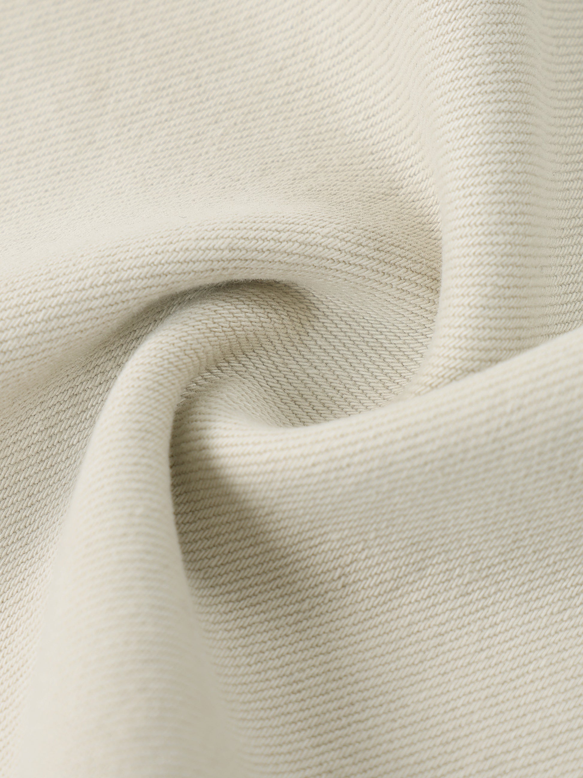 Close-up macro view of the premium heavyweight cotton denim fabric texture on women's beige streetwear jeans.