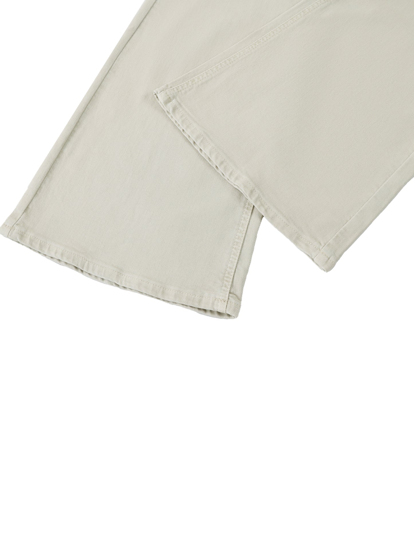 Close-up detail of the custom split-hem cut and stitched edge on the flared leg of women's beige vintage wash streetwear jeans.