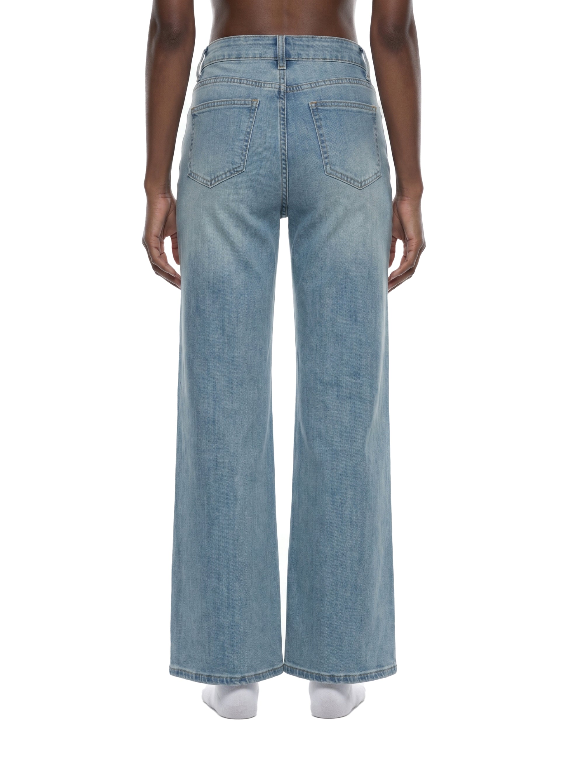 Rear view of a model wearing women's light blue flared jeans, showcasing the mid-waist fit, classic back pocket placement, and straight wide-leg silhouette.