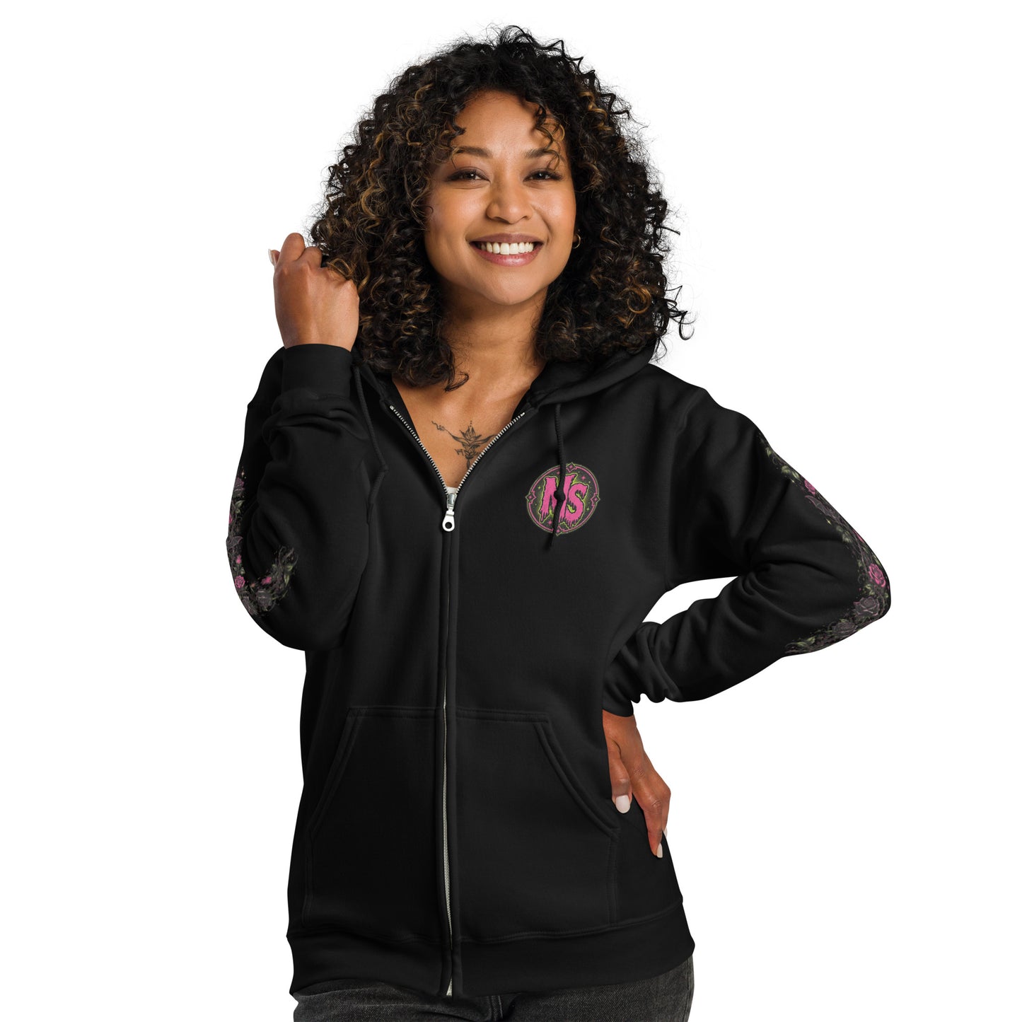 Smiling female model wearing a black unisex heavy blend zip hoodie with a pink circular chest emblem and floral sleeve print