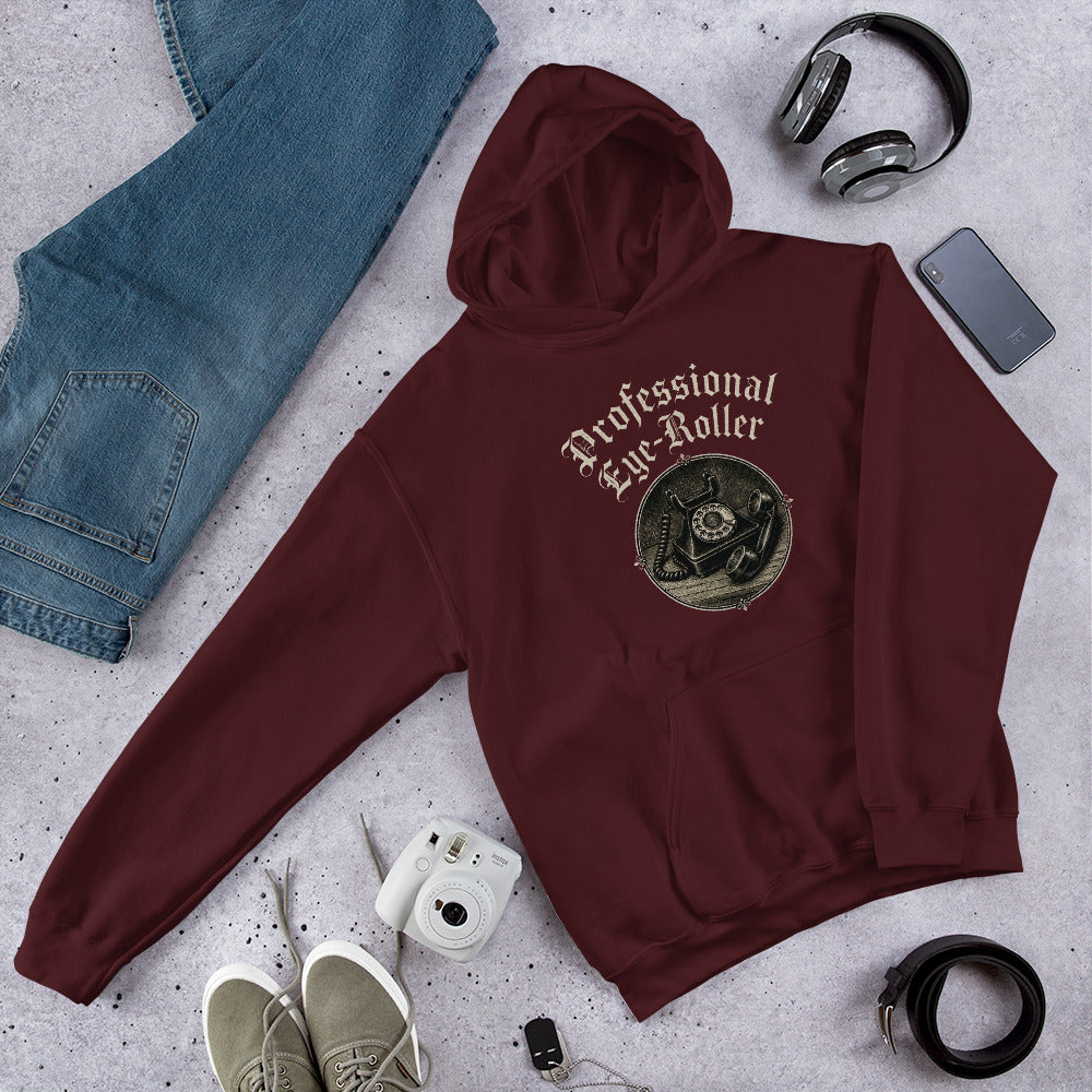 Folded flat lay styling of a maroon red unisex hoodie featuring a retro Professional Eye-Roller graphic with glasses and beanie