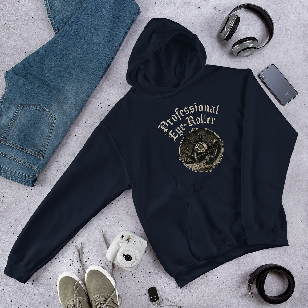 Folded flat lay styling of a navy blue hoodie featuring a retro Professional Eye-Roller graphic with white sneakers and sunglasses