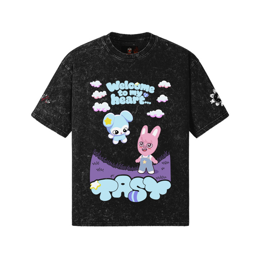 Front view of a Snow Wash dark grey vintage heavyweight t-shirt featuring a colorful graphic with the words "Welcome to my heart..." amidst clouds, DWAEKKI and TASY greeting, and "TASY" written at the bottom.