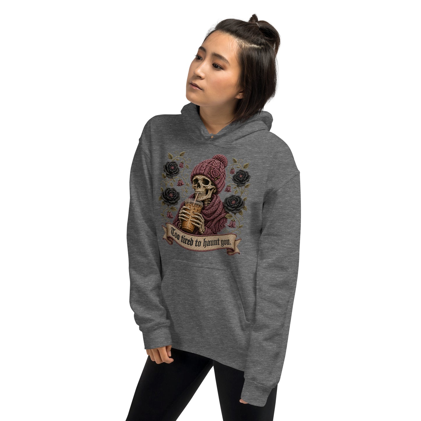 Female model wearing a graphite heather gray cozy hoodie with Too Tired to Haunt You skeleton print