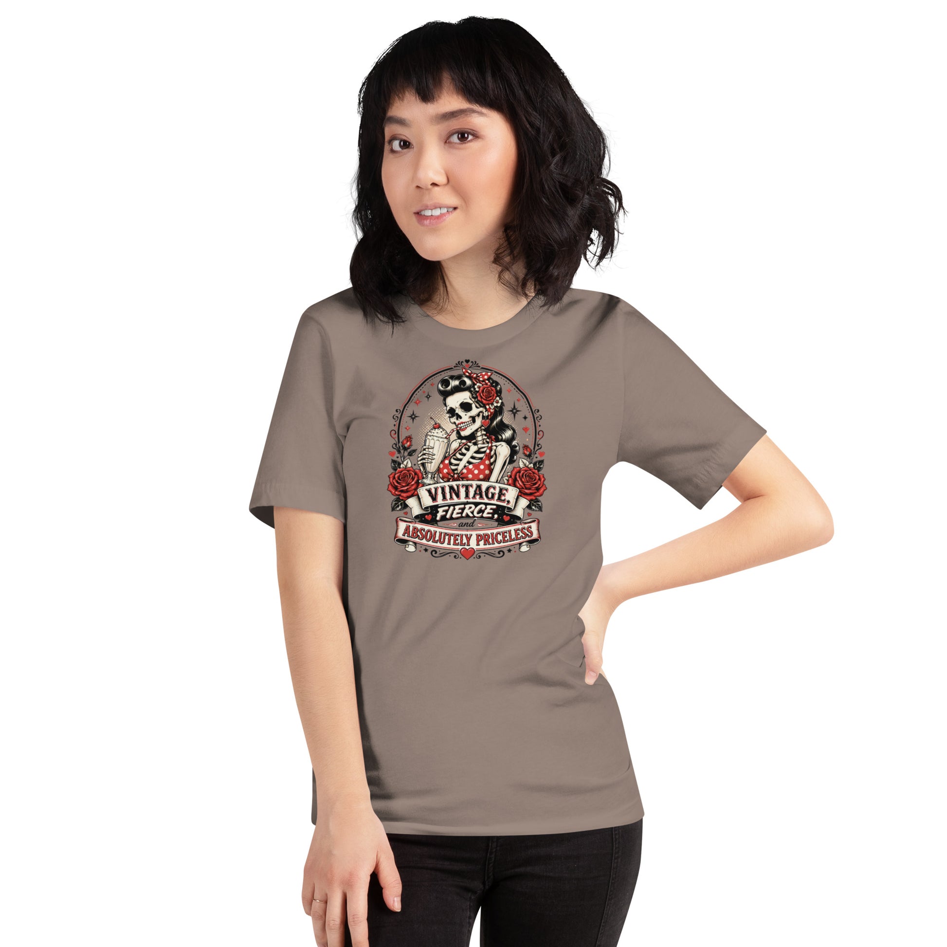 Front view of a female model wearing a pebble beige unisex graphic t-shirt featuring a rockabilly skeleton pinup girl with red roses and Vintage Fierce and Absolutely Priceless banner