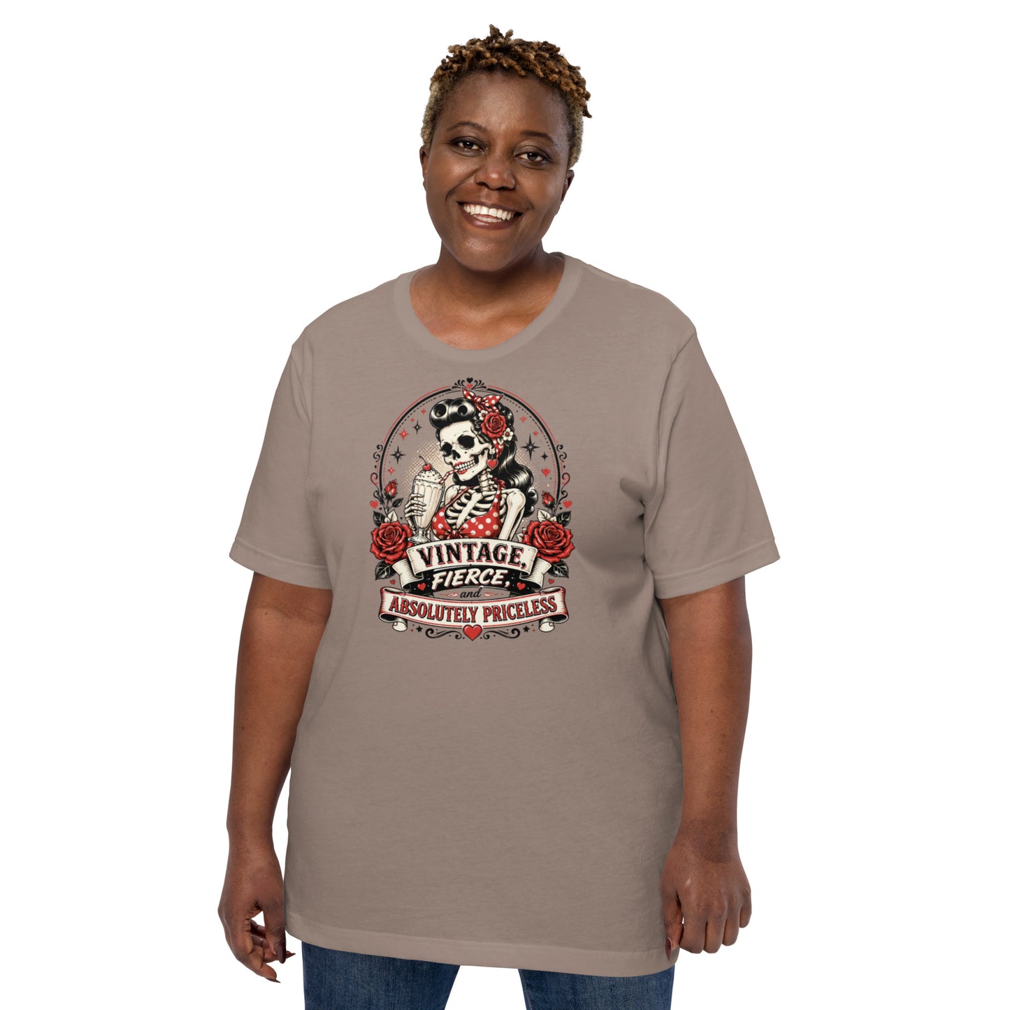 Front view of a smiling female model wearing a pebble beige unisex graphic t-shirt featuring a rockabilly skeleton pinup girl with red roses and Vintage Fierce and Absolutely Priceless banner