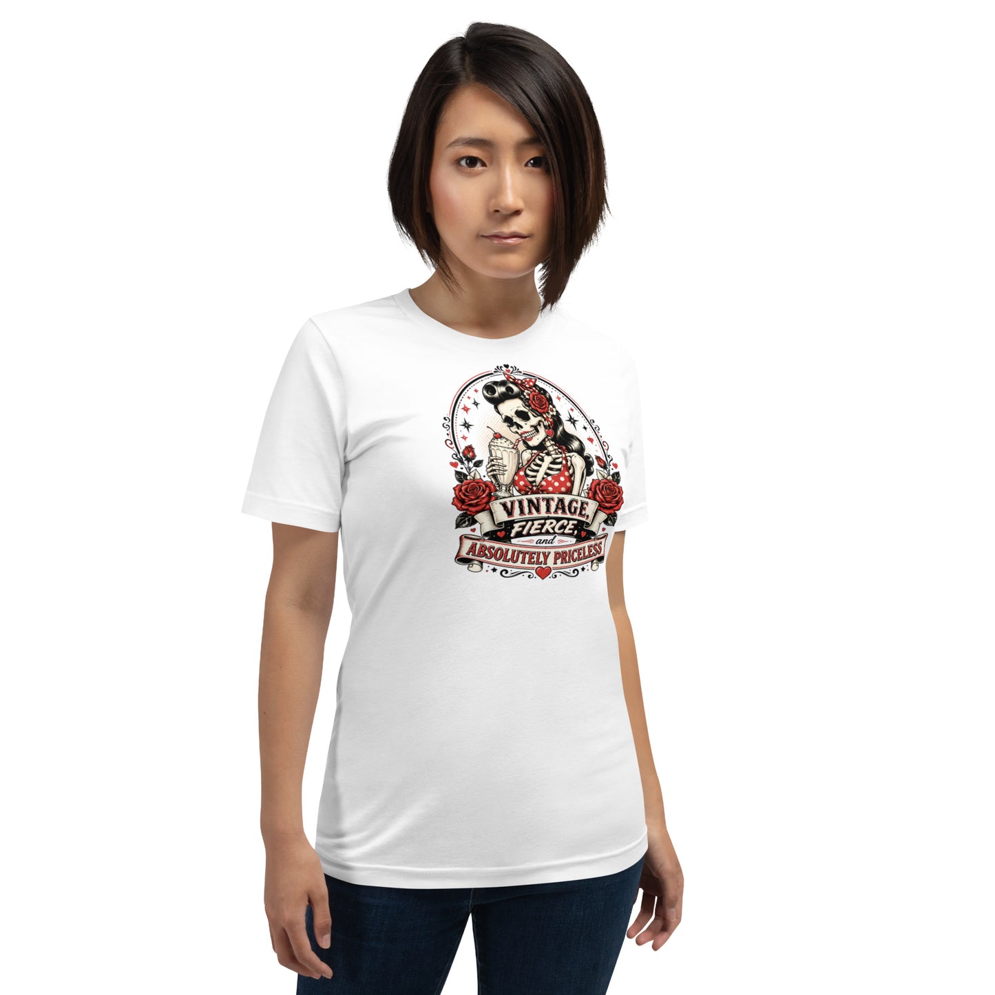 Front view of a female model wearing a white unisex graphic t-shirt featuring a rockabilly skeleton pinup girl holding a sundae with red roses and banner reading Vintage Fierce and Absolutely Priceless